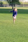 Chica corre sobre hierba hacia cámara - foto de stock