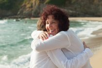 Dos mujeres abrazándose en la playa - foto de stock