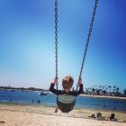 Boy sitting on swing on beach — Stock Photo
