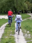 Familia hace ciclismo a lo largo de camino de tierra - foto de stock
