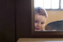 Garçon regardant par une fenêtre — Photo de stock