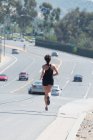 Mulher correndo estrada abaixo — Fotografia de Stock