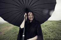 Mulher segurando guarda-chuva no vento — Fotografia de Stock