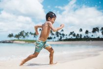 Niño corriendo a lo largo de la playa - foto de stock