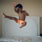 Хлопчик стрибає на ліжку в спальні — стокове фото