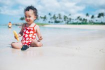 Petite fille assise sur la plage — Photo de stock