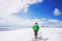 Мальчик идет вверх по холму в снегу — стоковое фото