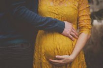 Пара тримає вагітний живіт — стокове фото