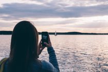 Woman taking photo of boat sailing — Stock Photo