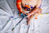 Bébé garçon recouvert de peinture multicolore — Photo de stock