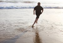 Niño corriendo en la playa - foto de stock