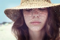 Portrait of teenage girl wearing straw hat with eyes closed — Stock Photo