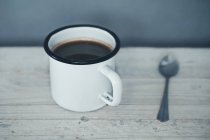 Mug of coffee and a soon on a table — Stock Photo
