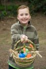 Junge hält einen Korb mit Ostereiern — Stockfoto