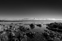 New Zealand, Kaikoura, monochrome image of rocky beach and mountains — Stock Photo