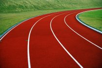 Primer plano de pista de atletismo brillante y hierba verde - foto de stock
