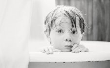 Крупним планом вид милого маленького хлопчика, який дивиться над краєм ванни — стокове фото