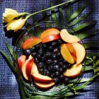 Plate of sliced apples and blueberries with flower decorations — Stock Photo