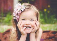 Сміється дівчина з квітами в волоссі дивиться на камеру — стокове фото