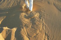 Обрізане зображення людини, що біжить піщаною дюною — стокове фото