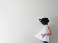Femme conceptuelle portant des vêtements en papier et les cheveux dans le vent debout devant fond blanc — Photo de stock