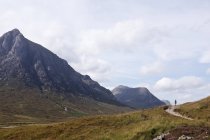 Mulher caminhando no caminho entre montanhas na Escócia — Fotografia de Stock