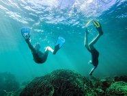 Мальчик и девочка плавают вместе под водой — стоковое фото
