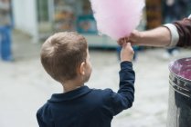 Вид ззаду маленького хлопчика, що тримає рожеву бавовняну цукерку — стокове фото