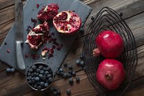 Frische Blaubeeren und Granatapfel auf Schiefer auf einem Küchentisch aus Holz — Stockfoto