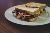 Bacon saboroso e sanduíches de ovo em uma chapa — Fotografia de Stock