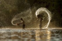 Концептуальний образ двох азіатських людей в золотих бризках води — стокове фото