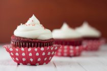 Tres cupcakes de terciopelo rojo en la mesa, enfoque selectivo - foto de stock