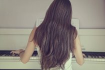 Visão traseira da menina tocando piano — Fotografia de Stock