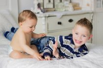 Bonito sorrindo irmãozinhos brincando na cama — Fotografia de Stock