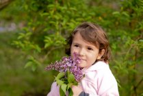 Kleines Mädchen mit einem Strauß fliederfarbener Blumen — Stockfoto