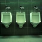 Linha de três urinóis no banheiro público — Fotografia de Stock