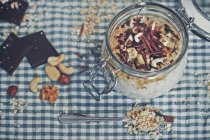 Porridge with chocolate, nuts and oats in jar over kitchen towel — Stock Photo
