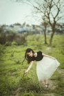 Chica usando vestido recogiendo plantas en la naturaleza - foto de stock