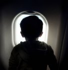 Rear view of boy looking through window on airplane, Spain, Madrid — Stock Photo