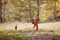 Boy chasing puppy dog in forest — Stock Photo
