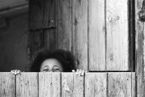 Menina se escondendo atrás da porta jogar esconder e procurar — Fotografia de Stock