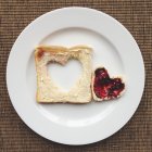Cuore in pane tostato con marmellata su piatto bianco — Foto stock