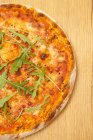 Крупный план вегетарианской пиццы с рукколой на деревянной поверхности — стоковое фото