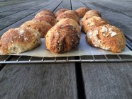Saborosos pães sourdough em rack de arame sobre mesa de madeira — Fotografia de Stock
