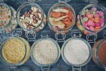 Linhas de jarros cheios de sementes, nozes, frutas secas e doces — Fotografia de Stock