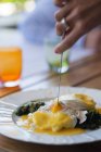 Female hand cutting into plate of eggs florentine — Stock Photo