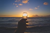 Scenic view of hand holding lightbulb at sunset — Stock Photo