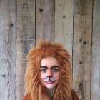 Adorabile bambina vestita in costume da leone su sfondo di legno — Foto stock