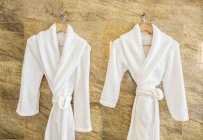 Two bathrobes on hangers in bathroom — Stock Photo