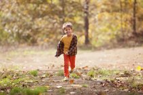 Niño feliz corriendo por el bosque de otoño - foto de stock